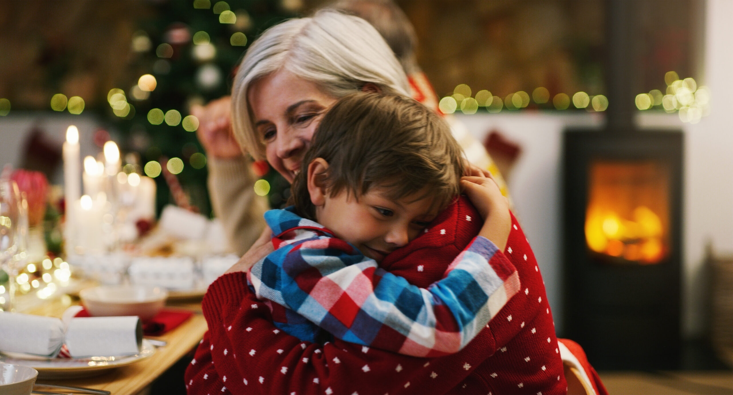 Christmas, love and a grandma hugging her grandchild in the home during the festive season together. Family, children or holiday with a young boy and senior woman in a house to hug while bonding