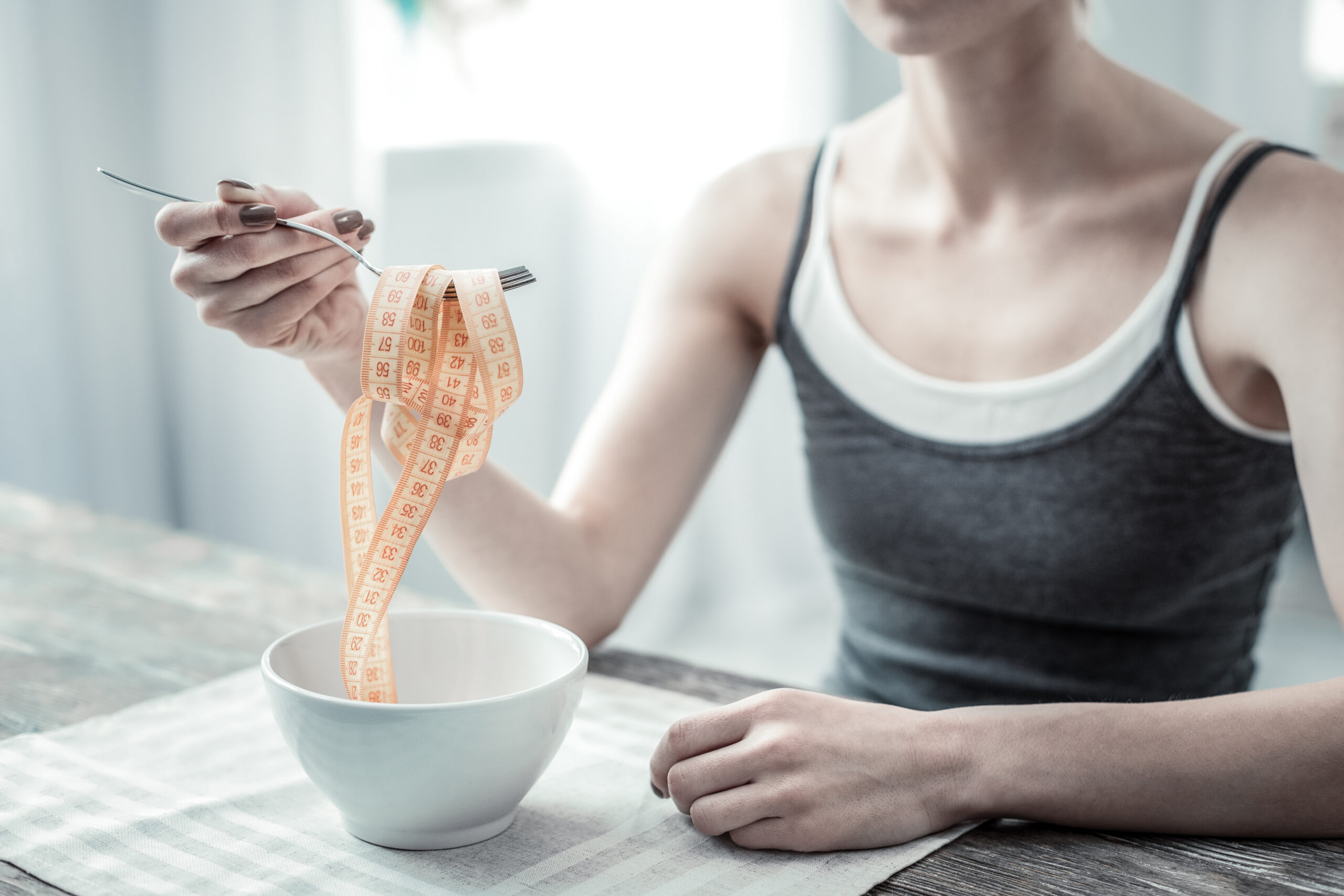 woman with an eating disorder hand that holding fork.