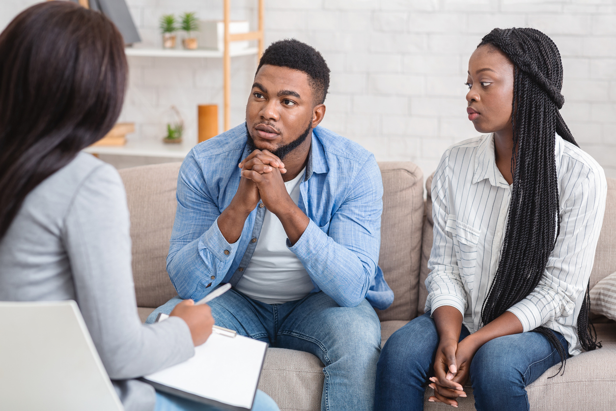 Couple Listening To Counselor's Advice Sitting On Sofa During Therapy Session