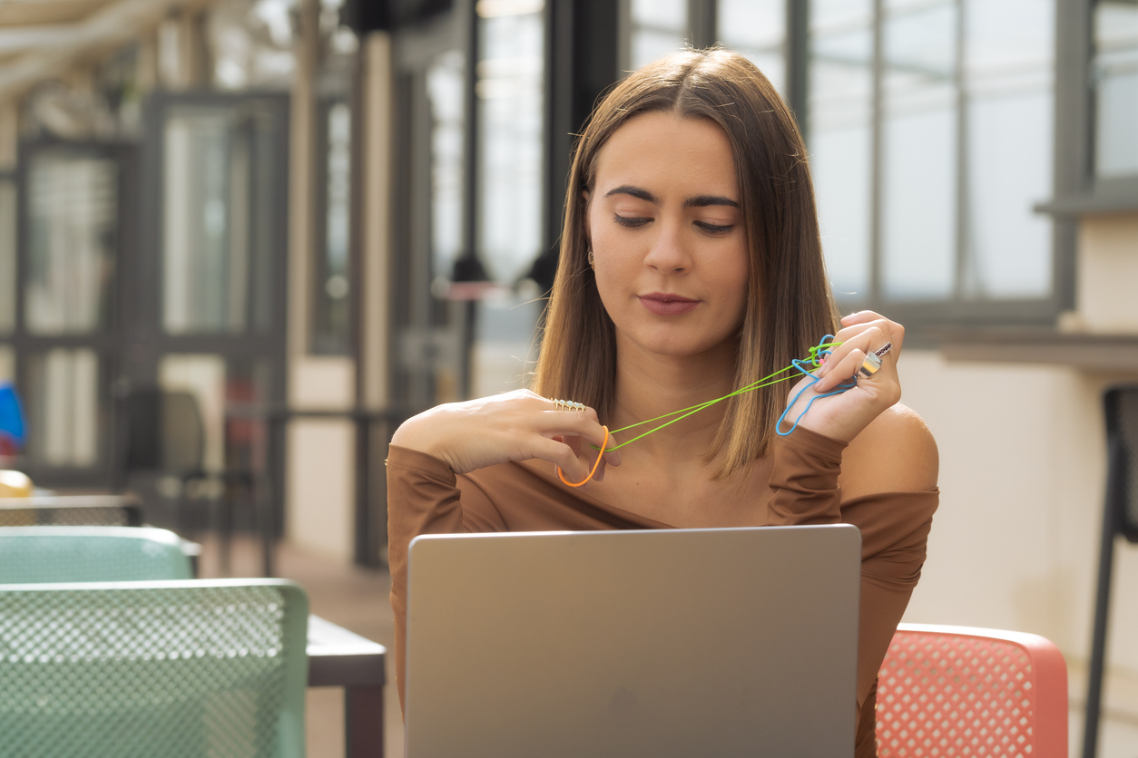 Young woman at work with a computer using objects, rubber bands, toys, and assistive devices for concentration.